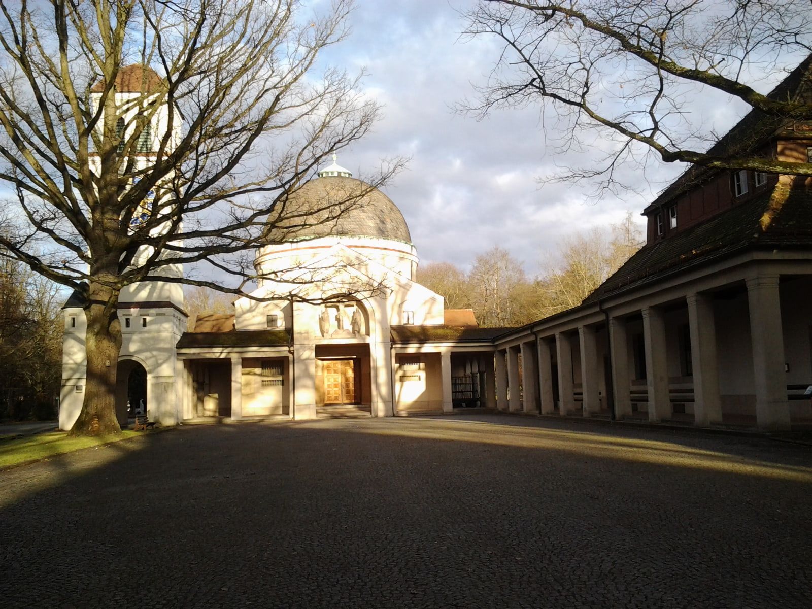 Gebäudekomplex mit großer Kuppel, hohem Glockenturm und langem Säulengang im Winterlicht auf Südfriedhof Nürnberg